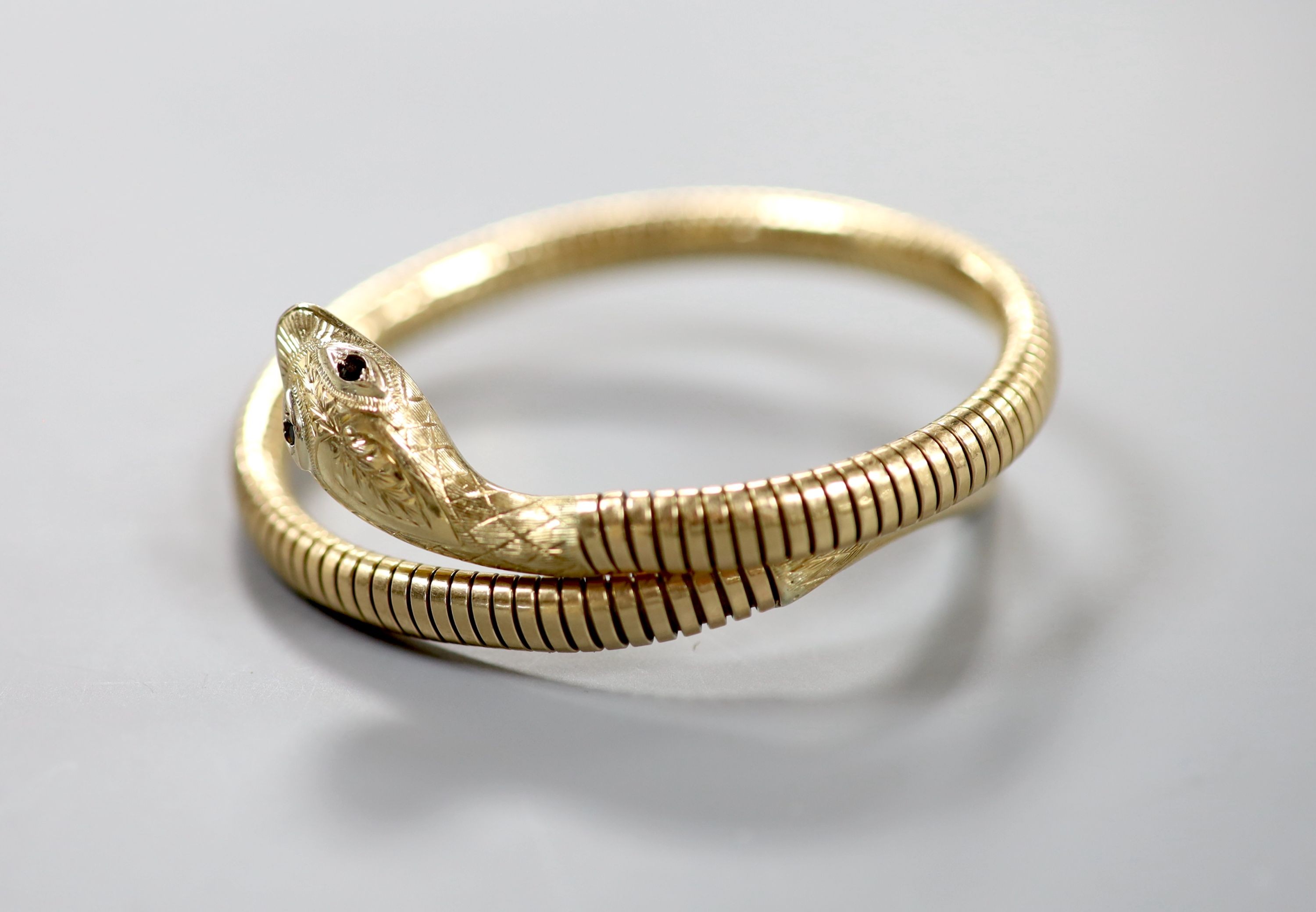A mid 20th century 9ct gold coiled serpent bracelet, with gem set eyes, gross weight 22.4 grams (metal spring) (a.f.).